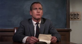 Movie still from “Torn Curtain” (1966), directed by Alfred Hitchcock – A man sitting at a table holding a book; Close Up shot, Low angle
