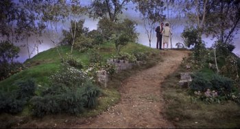 Movie still from “Torn Curtain” (1966), directed by Alfred Hitchcock – Two people standing on a dirt path next to trees; Extreme Wide shot, High angle