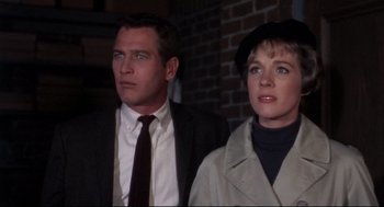 Movie still from “Torn Curtain” (1966), directed by Alfred Hitchcock – A man and a woman standing next to each other in front of a brick wall; Close Up shot, Low angle