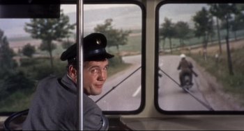 Movie still from “Torn Curtain” (1966), directed by Alfred Hitchcock – A man wearing a hat riding on a bus; Medium shot, Over the shoulder angle