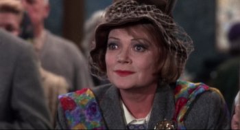 Movie still from “Torn Curtain” (1966), directed by Alfred Hitchcock – An older woman wearing a colorful suit and a hat; Close Up shot, Over the shoulder angle