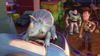Movie still from “Toy Story That Time Forgot” (2014), directed by Steve Purcell – A toy story character riding a triceratops car; Medium shot, High angle