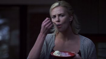 Movie still from “Trapped” (2002), directed by Luis Mandoki – A woman is holding a bowl of food while eating it; Close Up shot, Over the shoulder angle