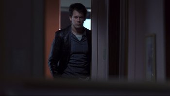 Movie still from “Trapped” (2002), directed by Luis Mandoki – A man standing in front of a door looking at the camera; Medium shot, Over the shoulder angle
