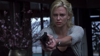 Movie still from “Trapped” (2002), directed by Luis Mandoki – A beautiful blond woman holding a gun in a room; Close Up shot, Low angle