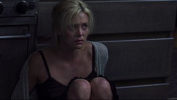 Movie still from “Trapped” (2002), directed by Luis Mandoki – A woman sitting on the ground in a dark room; Medium shot, Overhead angle