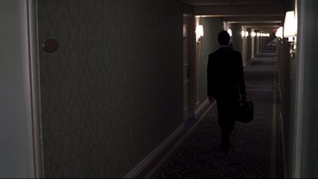 Movie still from “Trapped” (2002), directed by Luis Mandoki – A man in a suit walking down a hall way; Wide shot, High angle