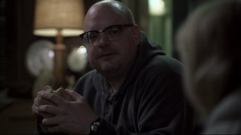 Movie still from “Trapped” (2002), directed by Luis Mandoki – A man with glasses is holding a piece of food; Close Up shot, Over the shoulder angle