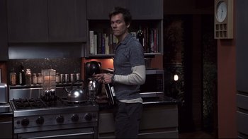 Movie still from “Trapped” (2002), directed by Luis Mandoki – A man standing in a kitchen holding a coffee pot; Medium shot, High angle