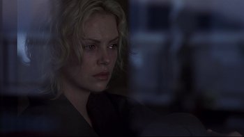 Movie still from “Trapped” (2002), directed by Luis Mandoki – A woman with blonde curly hair is looking out a window; Close Up shot, Over the shoulder angle