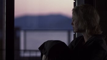 Movie still from “Trapped” (2002), directed by Luis Mandoki – A woman sitting in front of a window looking out at the mountains; Close Up shot, Low angle