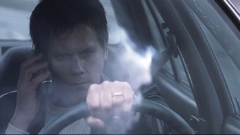 Movie still from “Trapped” (2002), directed by Luis Mandoki – A man driving a car with smoke coming out of the window; Close Up shot, Low angle