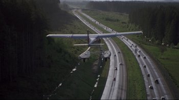 Movie still from “Trapped” (2002), directed by Luis Mandoki – An airplane is flying over a highway with cars on it; Extreme Wide shot, High angle