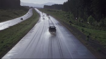 Movie still from “Trapped” (2002), directed by Luis Mandoki – Cars driving down a wet road on a rainy day; Extreme Wide shot, High angle