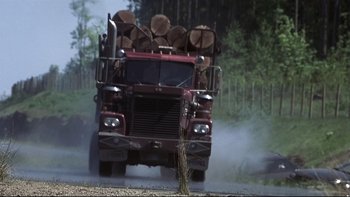 Movie still from “Trapped” (2002), directed by Luis Mandoki – A large truck driving down a dirt road near a forest; Wide shot, Low angle