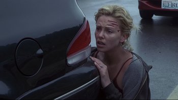 Movie still from “Trapped” (2002), directed by Luis Mandoki – A woman is leaning against a parked car; Medium shot, Over the shoulder angle