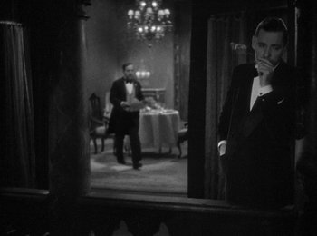 Movie still from “Trouble in Paradise” (1932), directed by Ernst Lubitsch – A black and white photo of a man in a tuxedo; Medium shot, Over the shoulder angle