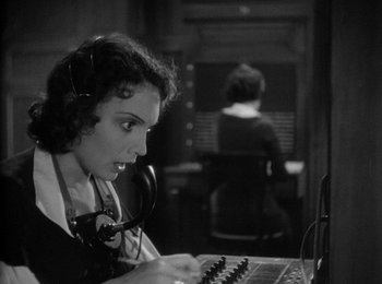 Movie still from “Trouble in Paradise” (1932), directed by Ernst Lubitsch – A woman with a headset is using a computer; Close Up shot, High angle