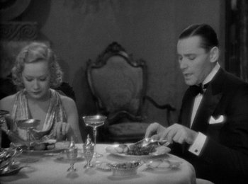 Movie still from “Trouble in Paradise” (1932), directed by Ernst Lubitsch – A man and a woman sitting at a dinner table; Medium shot, High angle