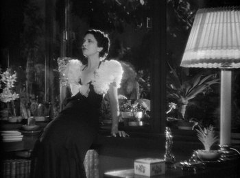 Movie still from “Trouble in Paradise” (1932), directed by Ernst Lubitsch – A black and white photo of a woman sitting on a window sill; Medium shot, Low angle
