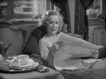 Movie still from “Trouble in Paradise” (1932), directed by Ernst Lubitsch – A black and white photo of a woman reading a newspaper; Medium shot, High angle