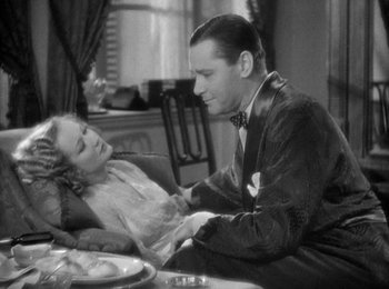 Movie still from “Trouble in Paradise” (1932), directed by Ernst Lubitsch – A man and a woman sitting at a dinner table; Medium shot, High angle