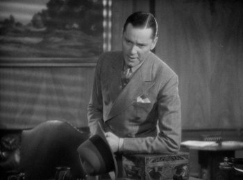 Movie still from “Trouble in Paradise” (1932), directed by Ernst Lubitsch – An old photo of a man in a suit and tie; Medium shot, High angle