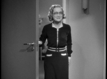 Movie still from “Trouble in Paradise” (1932), directed by Ernst Lubitsch – An older woman standing in a doorway wearing glasses; Medium shot, Over the shoulder angle