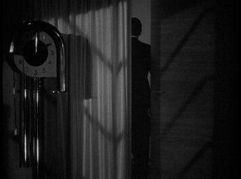 Movie still from “Trouble in Paradise” (1932), directed by Ernst Lubitsch – A man standing in front of a window with curtains; Wide shot, Low angle