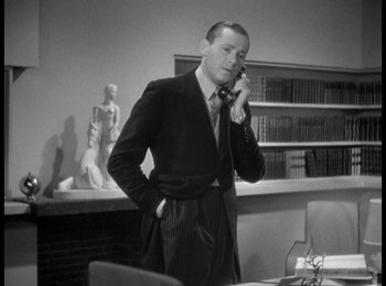 Movie still from “Trouble in Paradise” (1932), directed by Ernst Lubitsch – A black and white photo of a man talking on a phone; Medium shot, Low angle