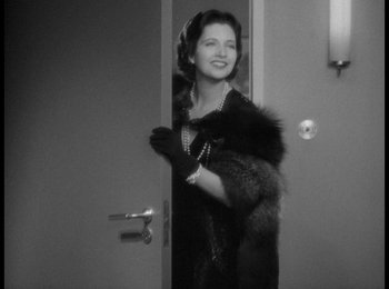 Movie still from “Trouble in Paradise” (1932), directed by Ernst Lubitsch – A black and white photo of a woman holding a fur coat; Medium shot, Over the shoulder angle