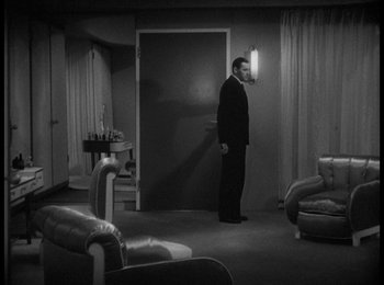 Movie still from “Trouble in Paradise” (1932), directed by Ernst Lubitsch – A black and white photo of a man standing in a living room; Wide shot, High angle