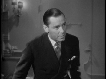 Movie still from “Trouble in Paradise” (1932), directed by Ernst Lubitsch – A man wearing a suit and tie in front of a wall; Close Up shot, High angle