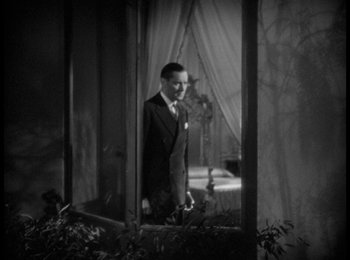 Movie still from “Trouble in Paradise” (1932), directed by Ernst Lubitsch – A black and white photo of a man in a suit and tie; Medium shot, High angle