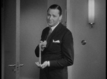 Movie still from “Trouble in Paradise” (1932), directed by Ernst Lubitsch – A black and white photo of a man in a suit and tie; Close Up shot, High angle