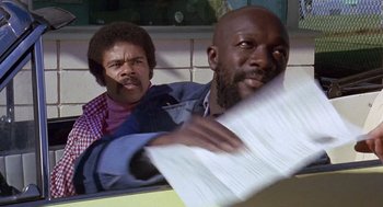 Movie still from “Truck Turner” (1974), directed by Jonathan Kaplan – A man and a woman holding papers in front of each other; Close Up shot, Low angle