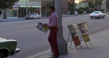 Movie still from “Truck Turner” (1974), directed by Jonathan Kaplan – A man standing on the side of the street holding a magazine; Wide shot, Low angle