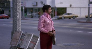 Movie still from “Truck Turner” (1974), directed by Jonathan Kaplan – A man standing on the side of the street holding a newspaper; Wide shot, Low angle