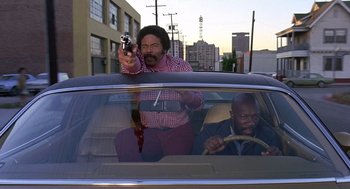Movie still from “Truck Turner” (1974), directed by Jonathan Kaplan – A man holding a gun while sitting in the back seat of a car; Medium shot, Low angle