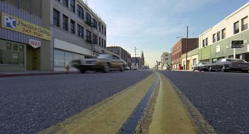 Movie still from “Truck Turner” (1974), directed by Jonathan Kaplan – A car driving down a street next to a fire hydrant; Extreme Wide shot, High angle