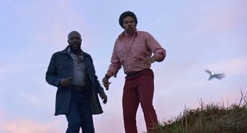 Movie still from “Truck Turner” (1974), directed by Jonathan Kaplan – Two men standing on top of a grassy hill; Medium shot, Low angle