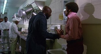 Movie still from “Truck Turner” (1974), directed by Jonathan Kaplan – Two men are talking in a kitchen with sinks; Medium shot, Low angle