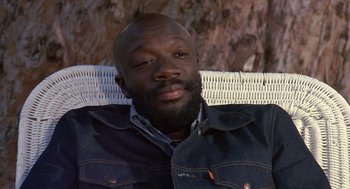 Movie still from “Truck Turner” (1974), directed by Jonathan Kaplan – A man sitting in a chair wearing a jean jacket; Close Up shot, Low angle