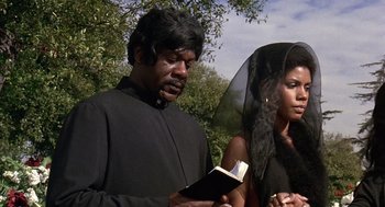 Movie still from “Truck Turner” (1974), directed by Jonathan Kaplan – A man and a woman standing next to each other holding an open book; Medium shot, Low angle