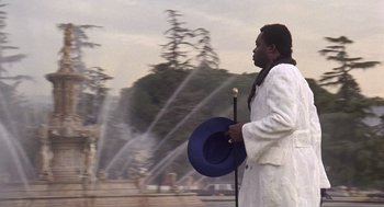 Movie still from “Truck Turner” (1974), directed by Jonathan Kaplan – A man in a white coat holding a blue hat; Medium shot, Low angle
