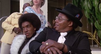 Movie still from “Truck Turner” (1974), directed by Jonathan Kaplan – A man and a woman sitting next to each other in front of other people; Close Up shot, Low angle