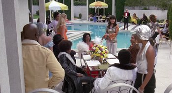 Movie still from “Truck Turner” (1974), directed by Jonathan Kaplan – A group of people sitting around a table; Wide shot, High angle