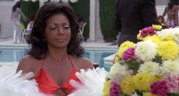 Movie still from “Truck Turner” (1974), directed by Jonathan Kaplan – A woman in a red top holding a bouquet of flowers; Close Up shot, Over the shoulder angle