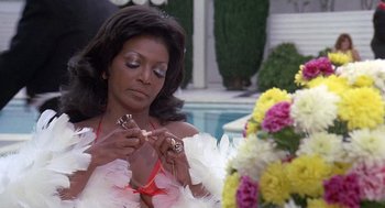 Movie still from “Truck Turner” (1974), directed by Jonathan Kaplan – A woman in a white dress holding a pair of earrings; Close Up shot, Low angle