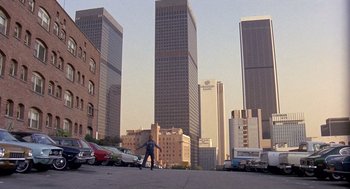 Movie still from “Truck Turner” (1974), directed by Jonathan Kaplan – A man riding a skateboard down the side of a street; Extreme Wide shot, High angle